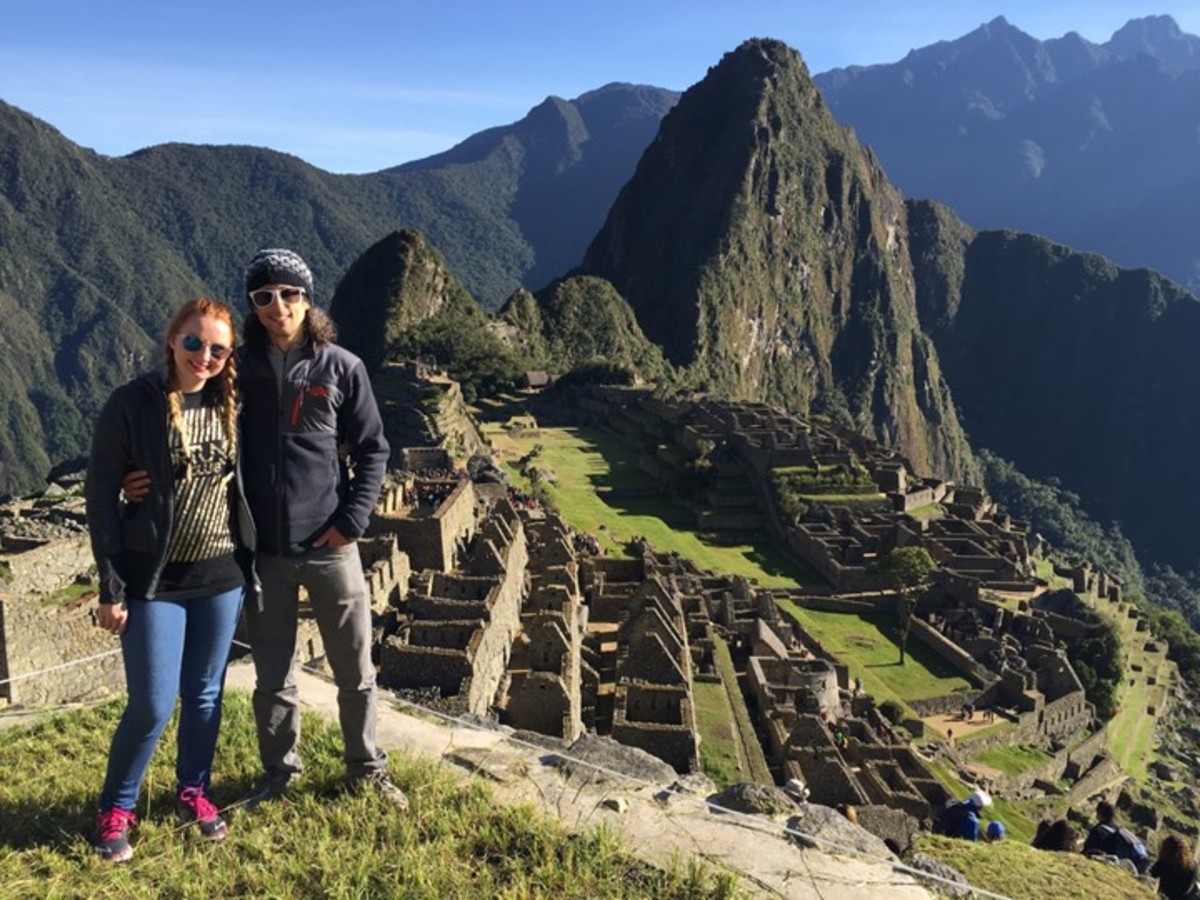 A photo of a man and woman smiling standing in front of Machu Picchu.