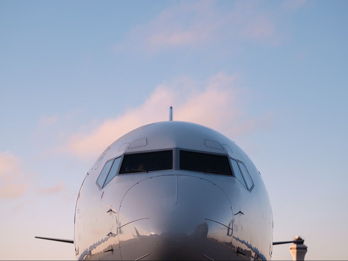 A photo of a plane with a blue and pink sky background.