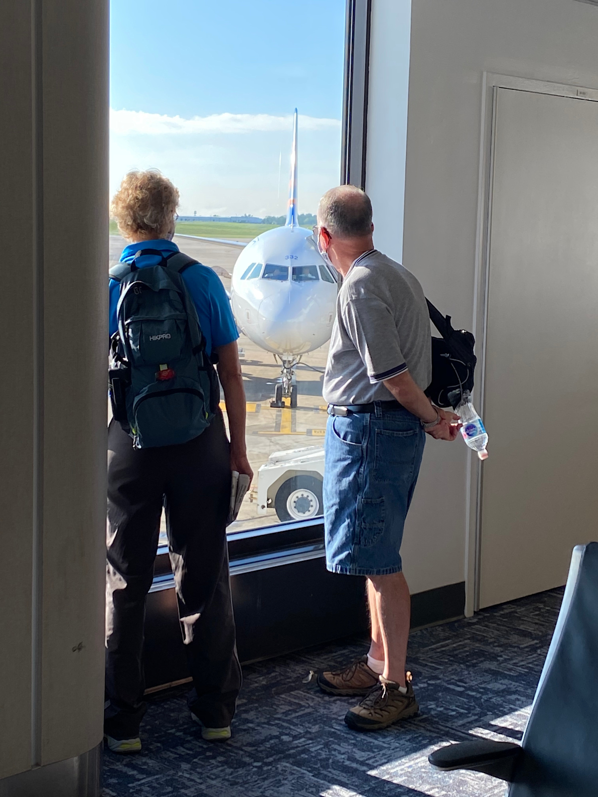 Two men looking through a window at a plane approaching