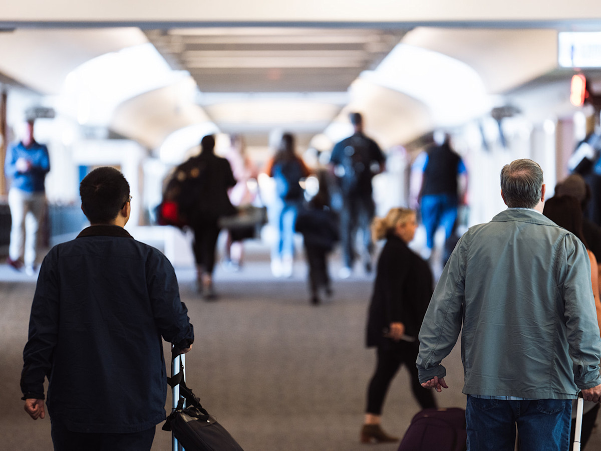 A photo of the backs of passengers walking through the Concourse at CVG Airport.