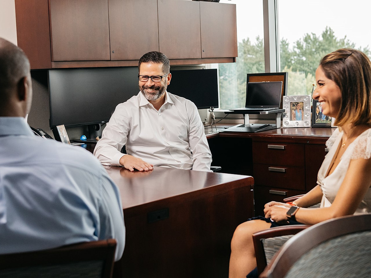 A photo of three employees happily chatting in an office.