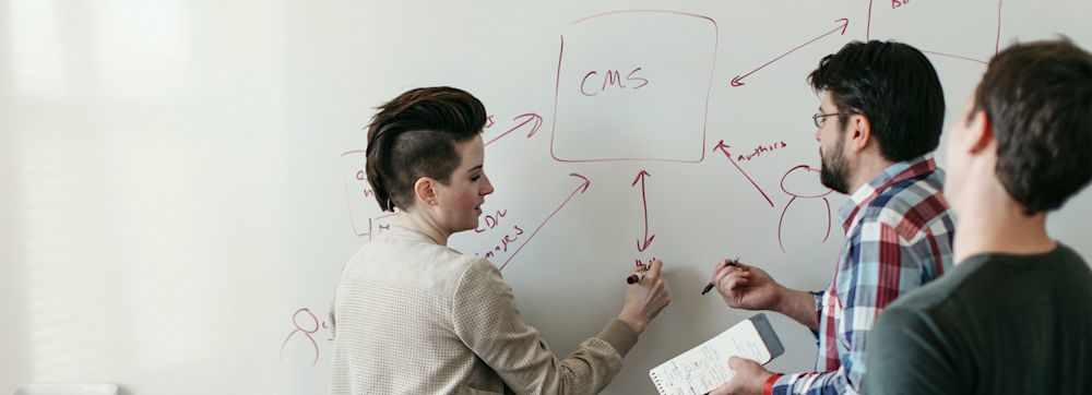 3 product designers and developers working on a whiteboard