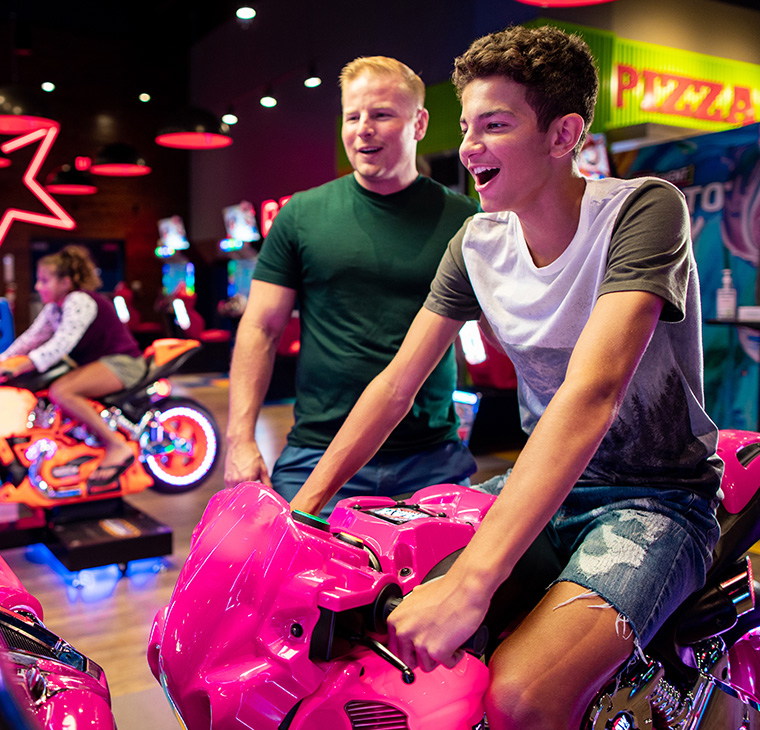 People playing motorcycle arcade game