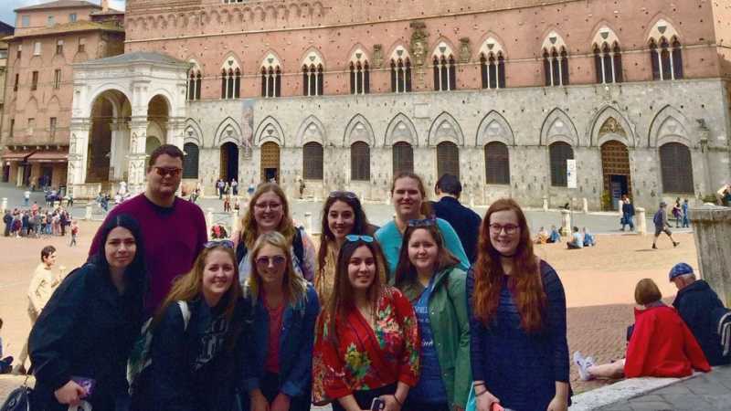 Students and professor's posing in front of the Palazzo Pubblico (Town Hall) palace in Siena, 托斯卡纳, 意大利中部.
