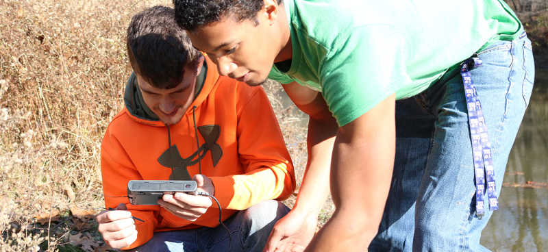Students are photographed measuring water levels on an on-site expedition through the Environmental Science program.  