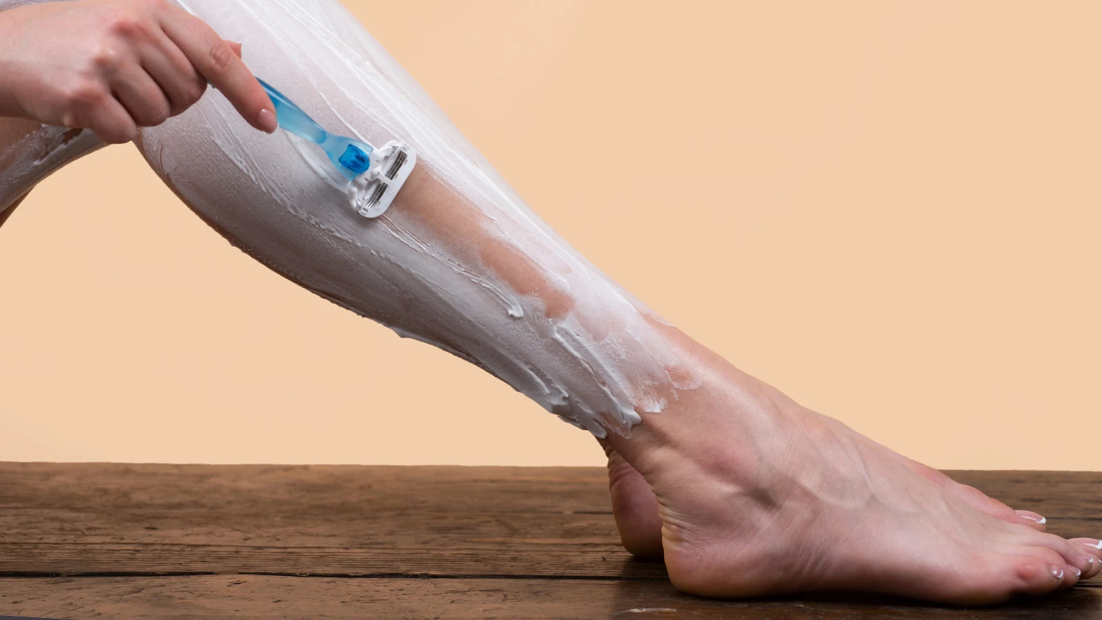 Woman shaving her leg with shaving gel