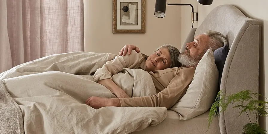 Mature couple hugging in bed - Sleep advice for couples.