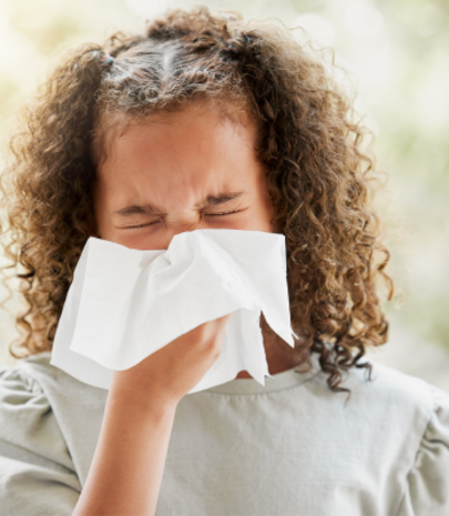 child blowing their nose with a tissue