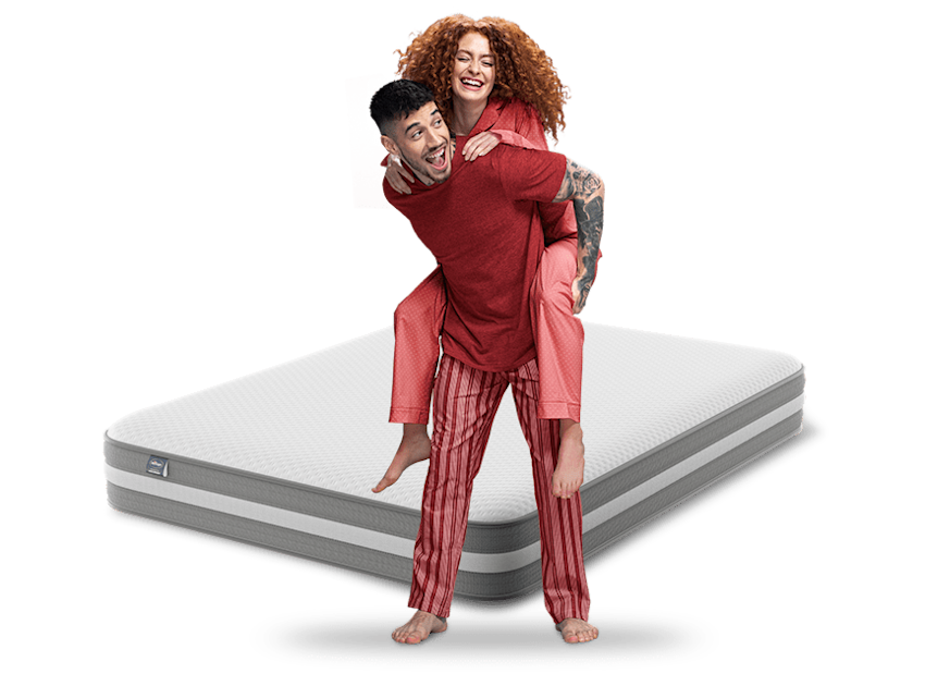 couple in red pyjamas with mattress behind
