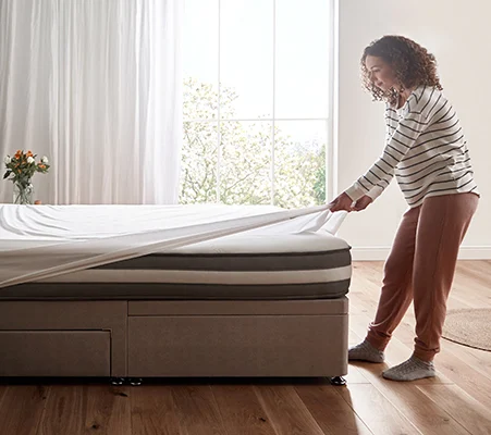 Woman putting fitted sheet onto mattress
