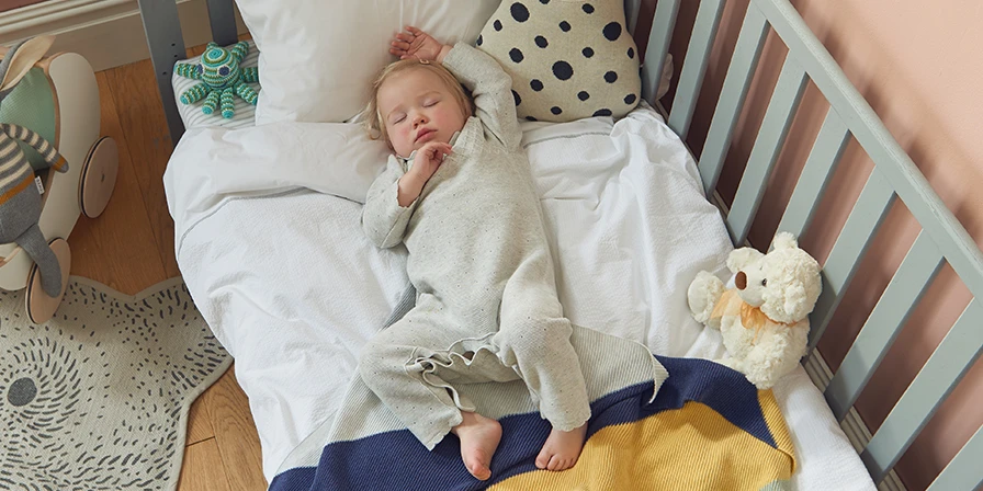 Sleeping baby on a cot bed in a nursery