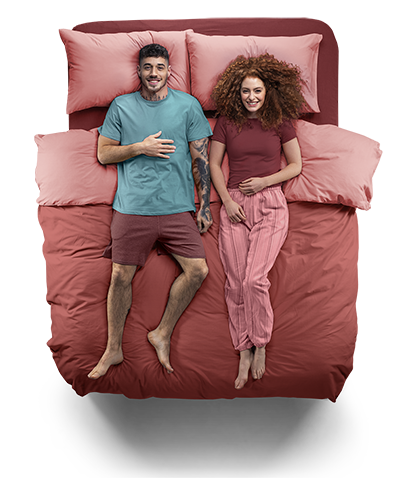 Top down view of a young couple laying on a STUDIO by Silentnight bed, smiling.