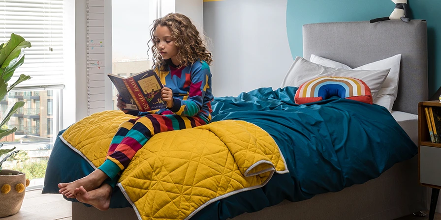 Child reading a book in her bedroom