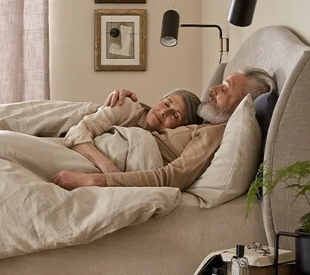 Mature couple hugging in bed - Sleep advice for couples.