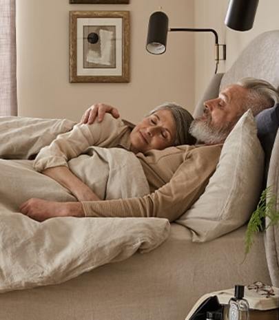 Mature couple hugging in bed - Sleep advice for couples.