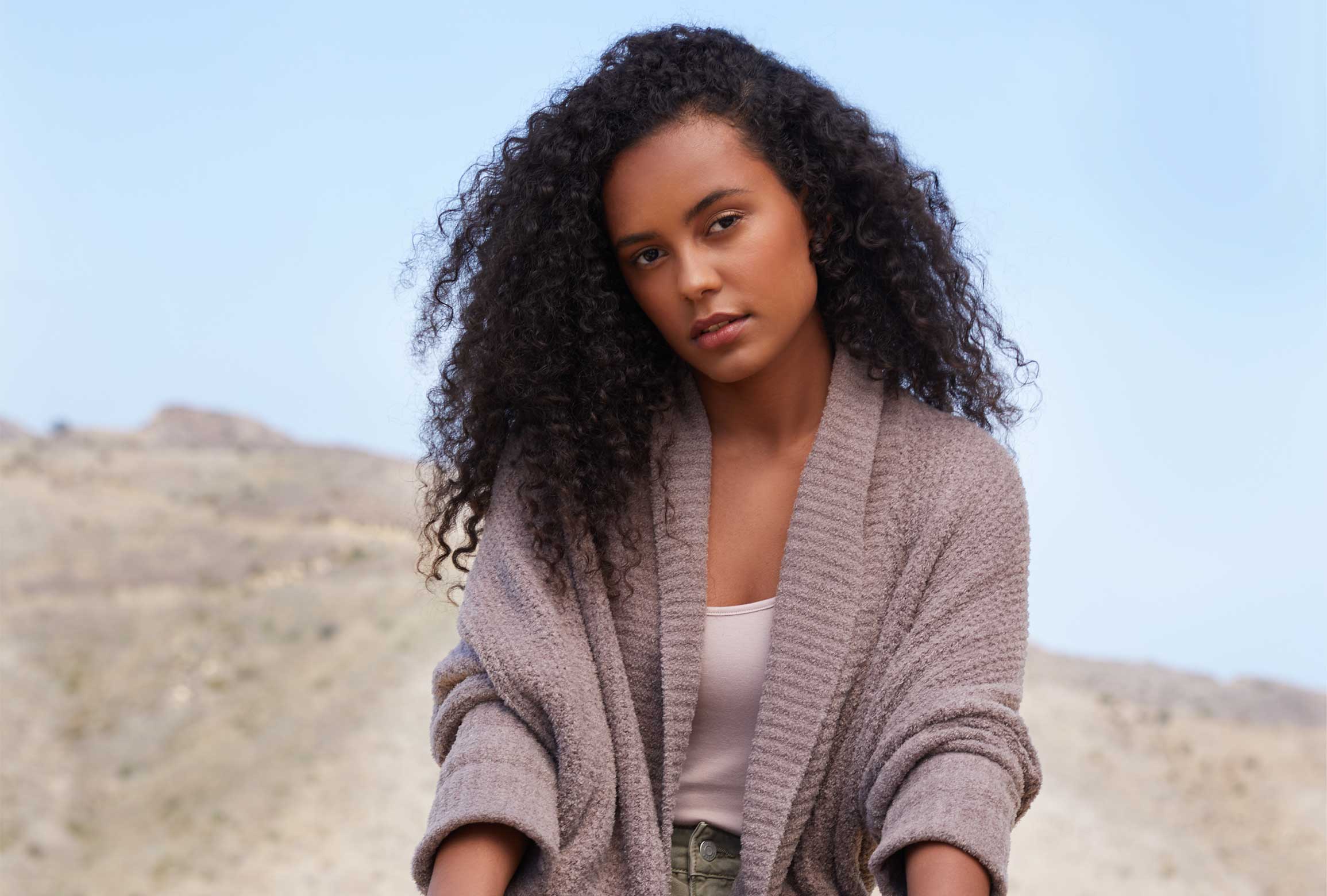 Woman sitting on rock with canyon view wearing cozy cardigan