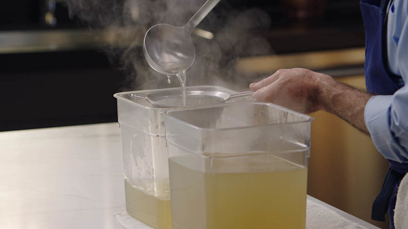 Thomas Keller straining chicken stock into plastic tubs