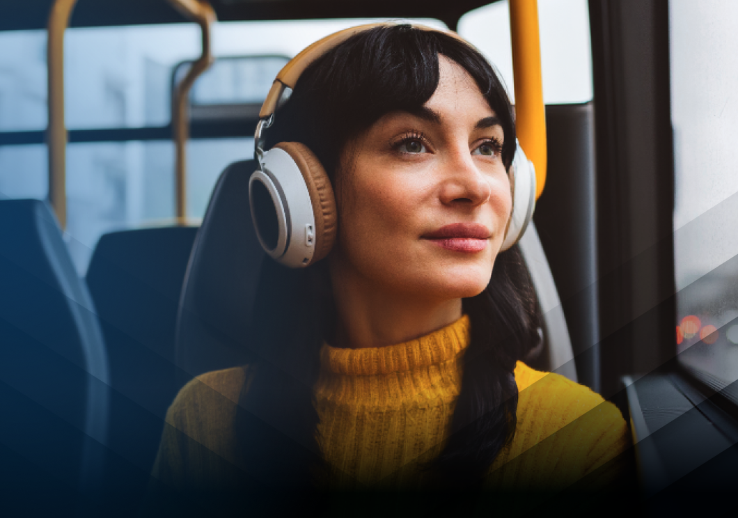 A woman wearing headphones while riding on a bus.
