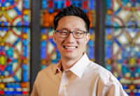 a man smiling with stained glass behind him