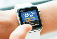 A close up of a person's wrist with Audible being used on Apple Watch. Trevor Noah's Audible book, Born a Crime, is displayed on it.