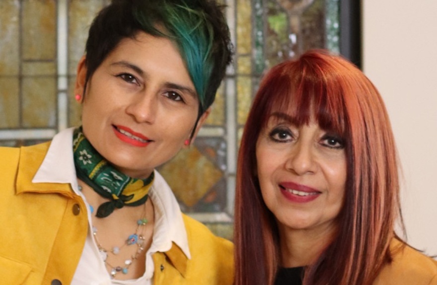 Artists Cazorla and Saleme pose in front of a stained glass window.