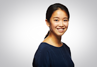 Jiun Kim is standing diagonally to the camera, smiling, and wearing a dark blue shirt.