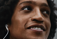 An image of a man listening to Audible on headphones while smiling.