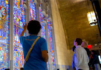 A group of 4 people are looking at the Innovation Cathedral's stained glass windows depicting multiple people throughout history who have contributed their own innovations in science and the arts.