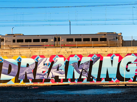 portion of a mural with the word "dreaming" under a bustling train station