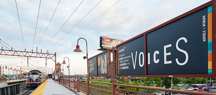 A train pulling into the Newark Broad Street Station with a poster about Audible displayed on the platform.