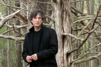 Neil Gaiman standing in a forest