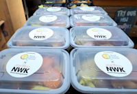 A stack of NWK meals are lined up on a table with labels.