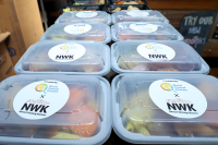 A stack of NWK meals are lined up on a table with labels.