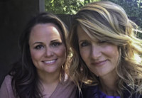 Producing partners Jayme Lemons and Laura Dern smile for the camera, their heads close together. The photo is cropped close so we see their heads and shoulders and some blurred trees in the background.