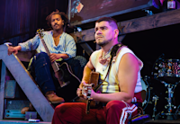 Nygel D. Robinson and Brian Quijada sit together onstage during a performance of “Mexodus.”