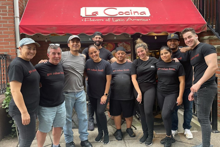 A group of people wearing La Cocina t-shirts post outside La Cocina restaurant.