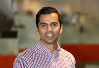 Abhinav Mathur is seen wearing a blue and red checked button-down shirt, looking straight at camera and smiling. The background behind him is blurred out.