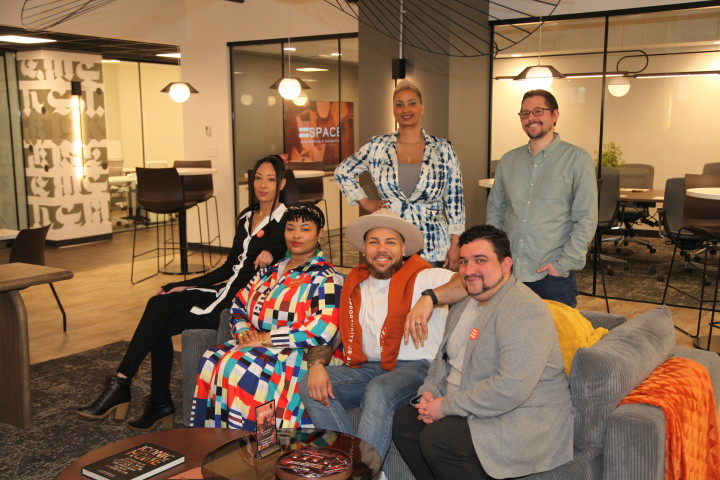 A group of people sitting on a sofa and standing inside an office space