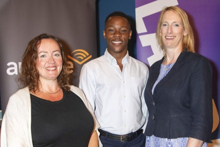 Three people post for a photo in front of an Audible sign and a LADMA sign.