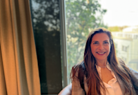 A photo of Jackie Levine, who's seated and smiling. She's wearing a blazer and white button-up shirt.