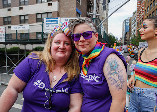 Two women posing closely together in purple #BeEpic shirts at the NYC Pride March.