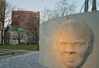 a sculpture of a person's face in a park with buildings in the background