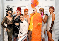 Sasha Velour's drag revue, NightGowns, stands against a photo backdrop featuring the Tribeca Festival, Audible and AT&T logos.  Sasha Velour is squatting down in front of the six drag queens that make up the review.