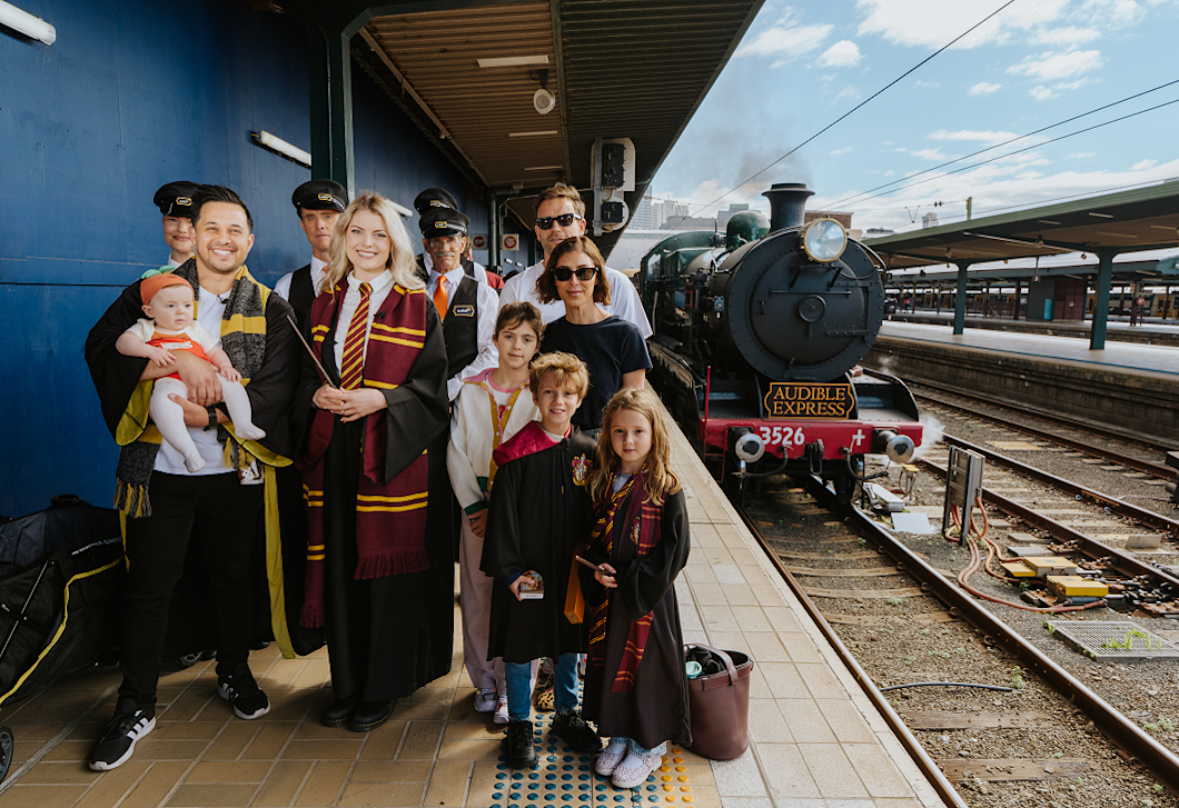 Harry Potter fans stand together on a platform, getting ready to board the Audible Express vintage steam train in Sydney.