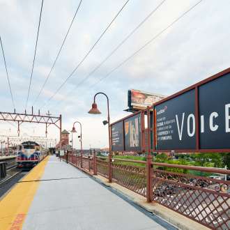 A train pulls into Broad Street Station in Newark, which is only blocks from Newark's headquarters. A billboard about Audible lines the platform.