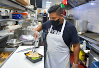 A cook from a NWK participating restaurant prepares a grilled chicken meal.