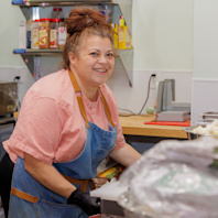 A woman stands in a kitchen prepping food.