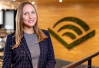 Audible employee Julia Phillips stands in the Newark office, the Audible chevron on the wall behind her.
