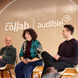 Three people sit in chairs on a stage for a panel. On the wall behind them are the Sundance Collab and Audible logos.