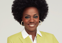 Viola Davis smiles at camera, wearing a citrine colored blazer and white blouse.